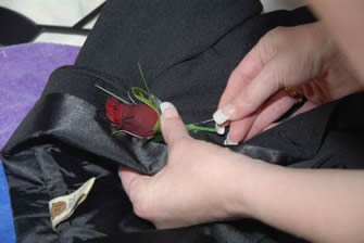 Much easier to pin on a buttonhole with the jacket off.  Left lapel. Stem pointing down.