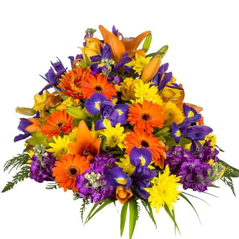 bright funeral casket spray showing full length for top of coffin. Mixed bright colourful flowers in season.