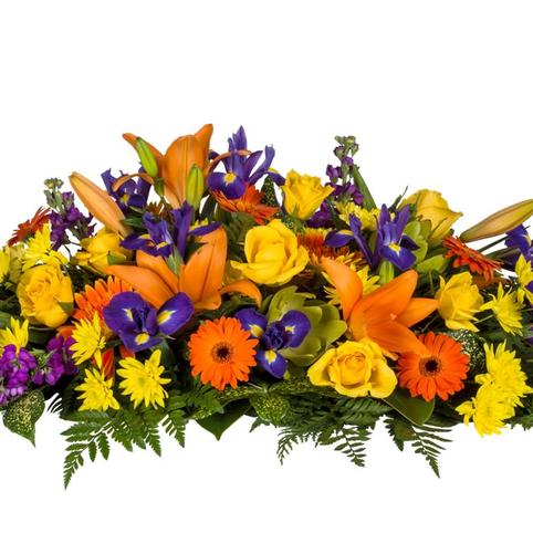 side view bright casket spray flowers. Purple Iris, orange lilies, orange gerberas, yellow roses, foliages.