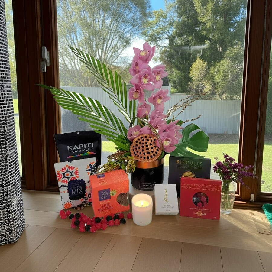 Cymbidium orchid gift box with candle and gourmet treats in styled scene