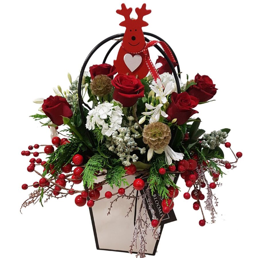 Christmas floral design with wooden reindeer, red roses and red berries