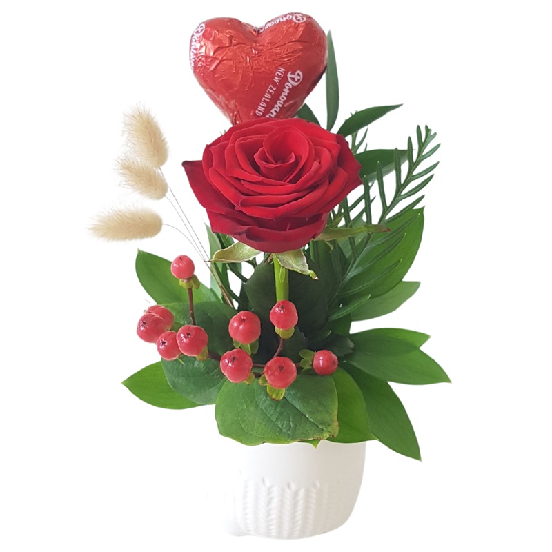 red rose and a chocolate heart arranged in a white ceramic pot