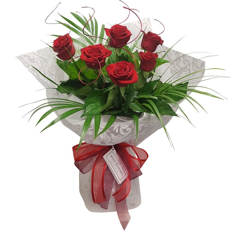 Bouquet of 6 Red Roses and tropical palm leaves for Valentines Day in florentine white wrapped water filled vox box with a mixture of red and burgundy chiffon ribbon.