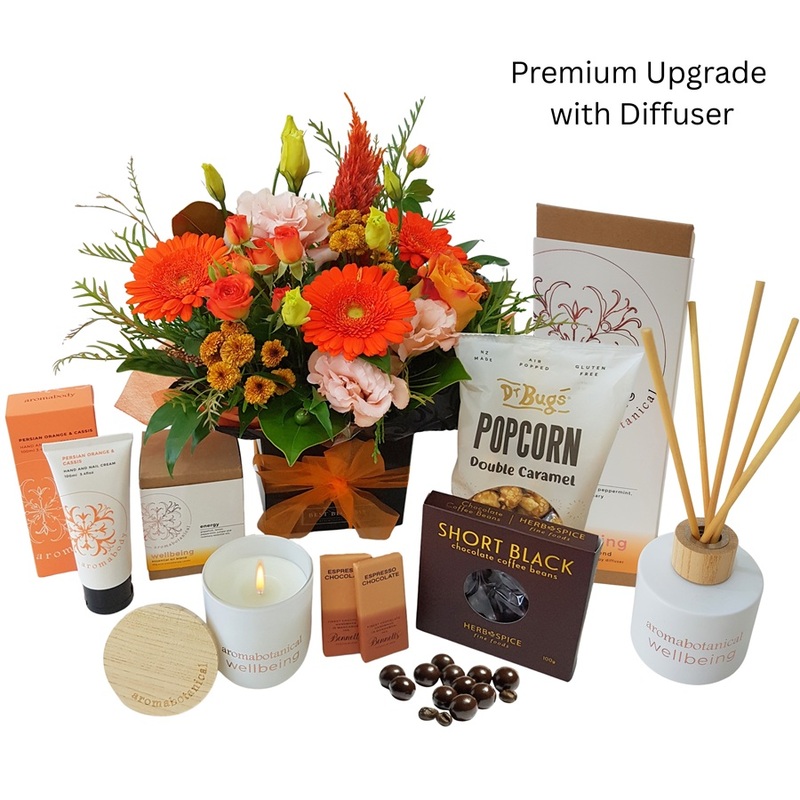 Energy boost wellness gift basket with candle, chocolates, popcorn and coffee beans and scented diffuser sticks.