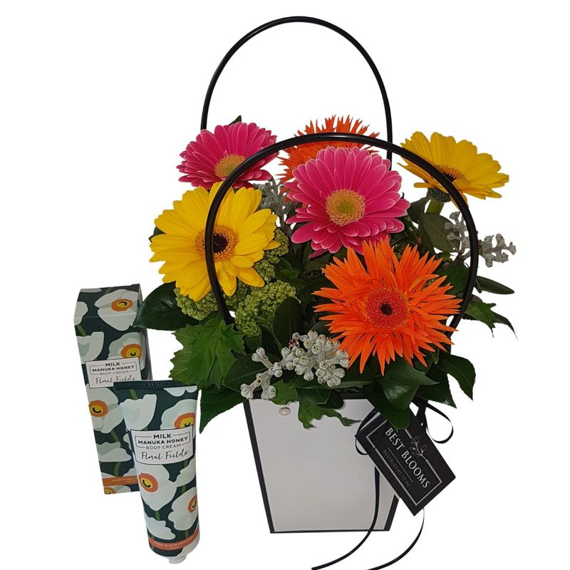 Colourful Gerbera flowers in handbag with candies and hand cream