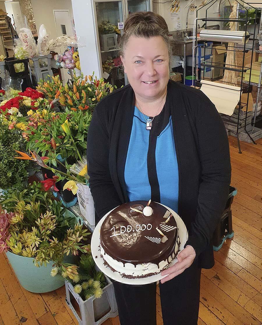 owner Best Blooms Florist Jo-Ann Moss with cake celebrating 100,000 flower orders.