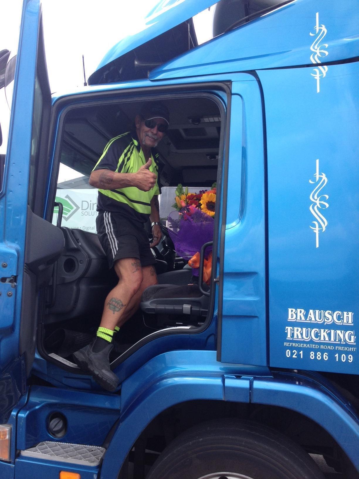 smiling truck driver man in green shirt holding bright flowers